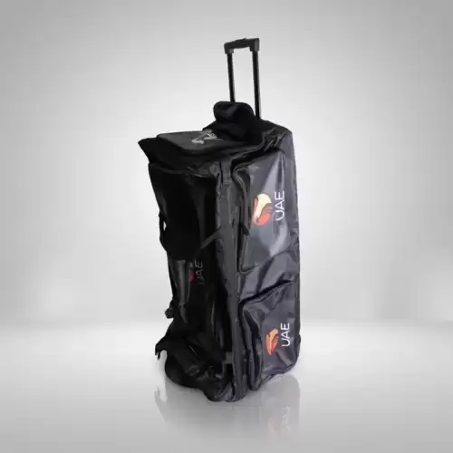 AR Sports Coffin Cricket Kit Bag shown against a clean white and light gray studio background. The black cricket kit bag stands upright in the center, featuring a tall, rectangular coffin-style design with multiple zippered compartments, reinforced fabric panels, and side pockets for storing cricket equipment. Two AR Sports UAE logos with red, yellow, and orange graphics are visible on the side compartments. A telescopic pull handle extends from the top, making the bag convenient to transport, while its wheeled design supports easy movement. The bag has a durable-looking black exterior with visible stitching, zippers, and separate storage sections for organizing cricket gear. The image showcases the AR Sports Coffin Cricket Kit Bag, designed for cricketers who need practical storage and transportation for their equipment, available for online purchase and home delivery across Pakistan.